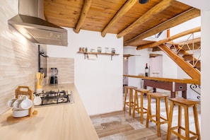 A modern kitchen with a gas stove, wooden stools, and a bar area with stools.