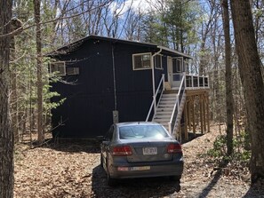 A cabin with a car parked in front, surrounded by trees.