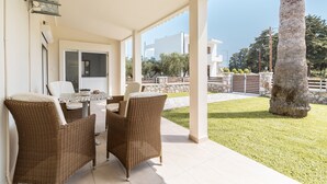 A covered patio area with wicker furniture, a table, and chairs.
