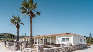 A single-story building with a stone foundation, a tiled roof, and a porch with benches.