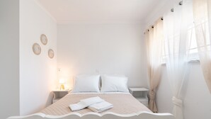 A neatly made bed with white linens, a bedside table with a lamp, and a wall with three circular wall art pieces.