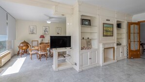 Una sala de estar con televisión, sillas de madera, un globo terráqueo y una estantería.