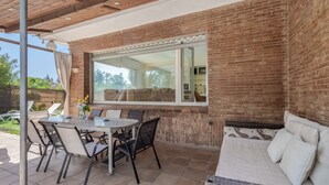 Un patio con una mesa y sillas, un sofá y un ventanal grande con vistas a un jardín.