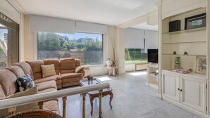 Un salón amplio con un gran ventanal, un sofá color beige, una mesa de centro y un televisor.