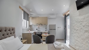 Una camera d'albergo compatta con un letto, un piccolo tavolo da pranzo, angolo cottura e bagno.