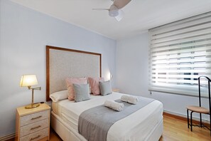 Un lit bien fait, avec des oreillers, une lampe de chevet, une chaise et une fenêtre avec des stores.