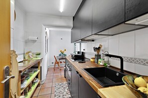Cocina moderna con encimera de madera, pileta negra y comedor con una silla y mesa.