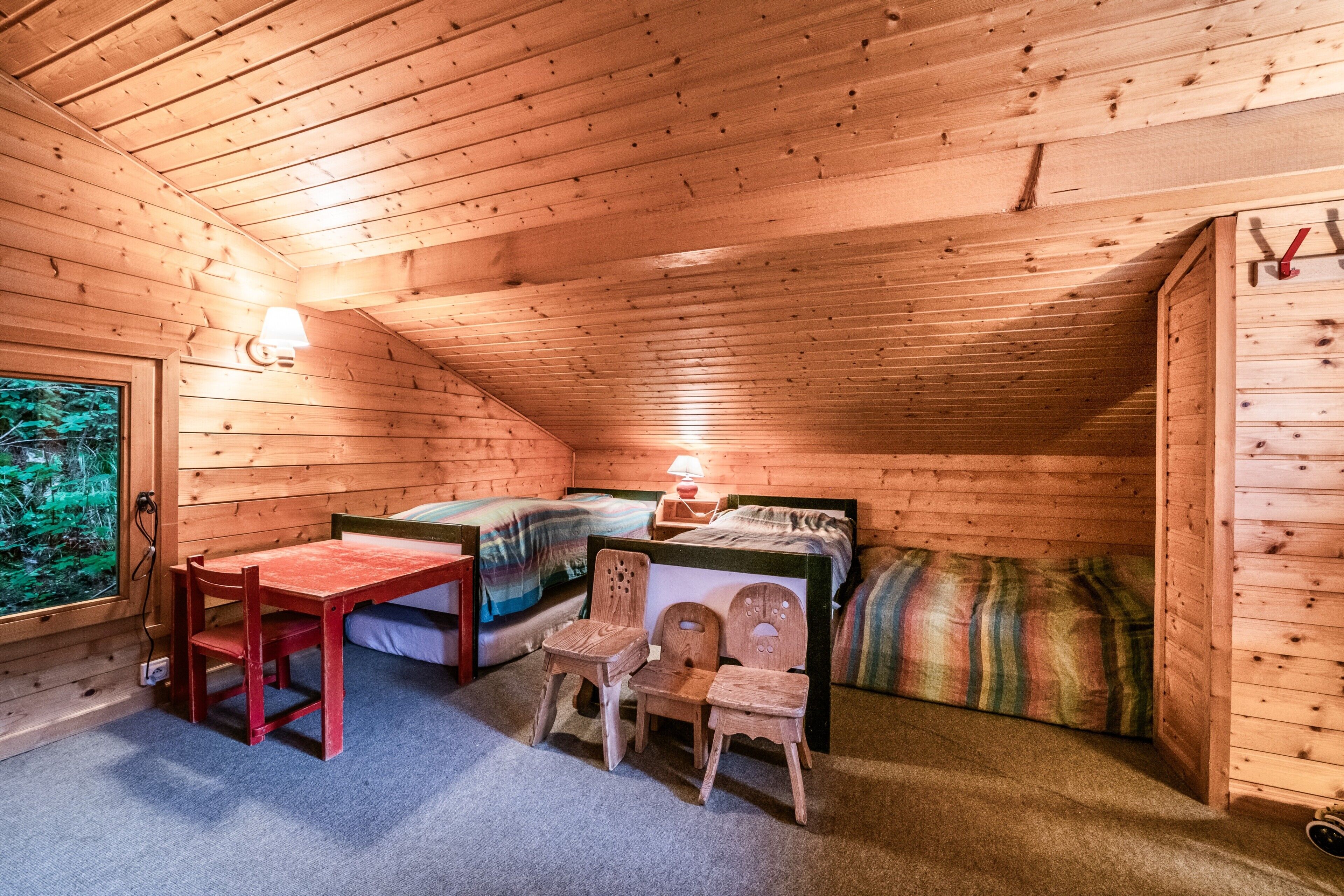 A wooden cabin room with a bed, a table, and two chairs.