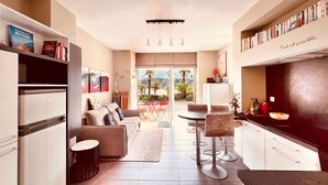 A modern kitchen with a dining area, a sofa, and a view of the outdoors. - Brittany Dream in Perros-Guirec – Sea View, Private Terrace, Ideal for Remote Work – High-Speed Wi-Fi (Perros-Guirec)
