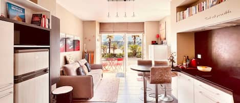 A modern kitchen with a dining area, a sofa, and a view of the outdoors.