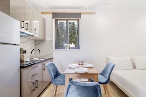 A compact kitchen with a dining area, a window with a view, and a bed.