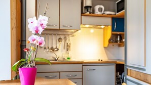 Een moderne keuken met witte kasten, een houten aanrechtblad en een roze vaas met bloemen.