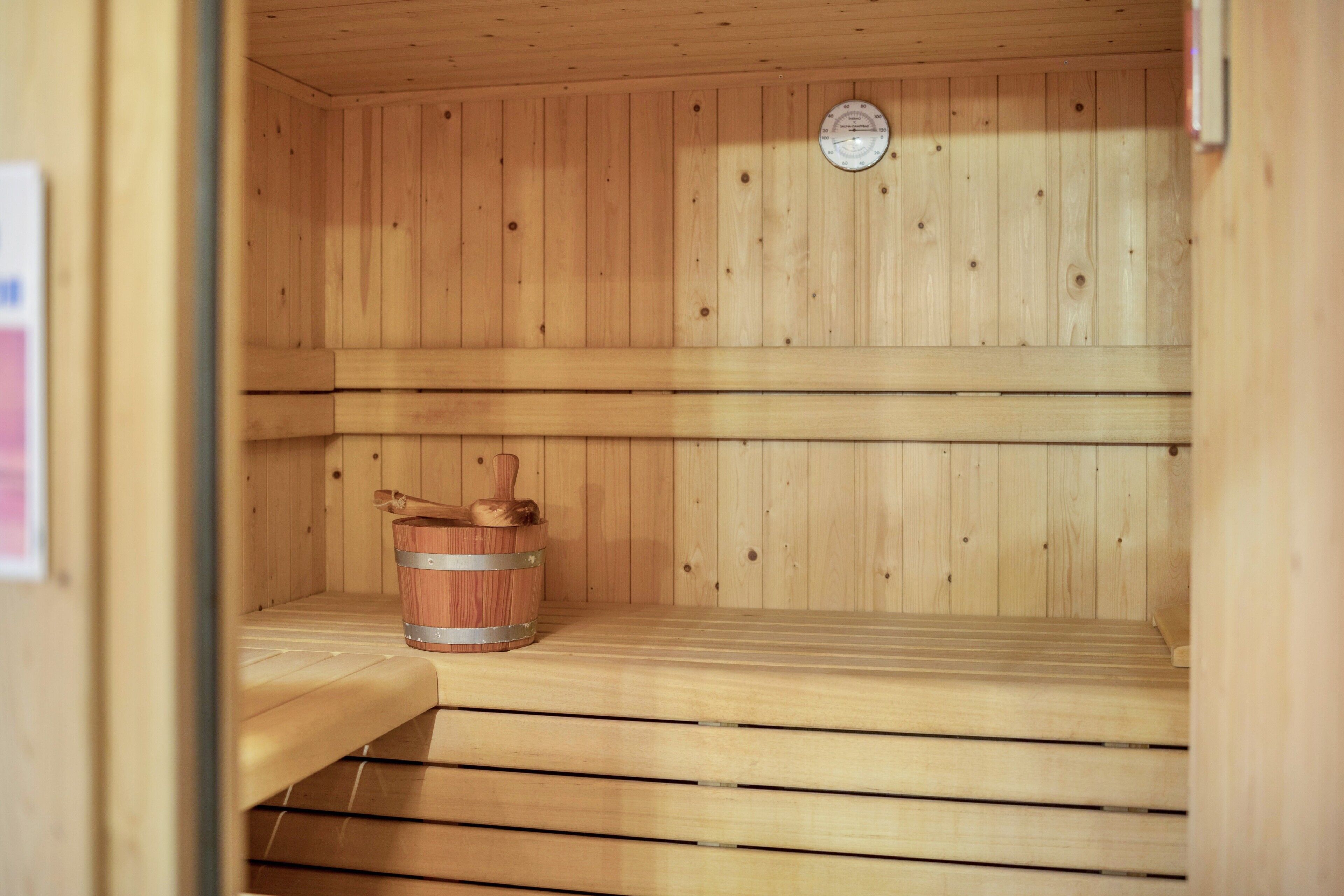 Una sauna de madera con bancos y un cubo de madera.