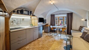 A compact kitchen with modern appliances, a dining area with a round table and chairs, and a cozy seating area with a sofa and a small side table. - Residence Grünbacher Apartment 2 with Balcony and Shared Pool (Issengo)