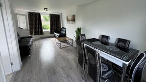 Un salon moderne comprenant un canapé, une table à manger avec des chaises, une table basse et une plante en pot.