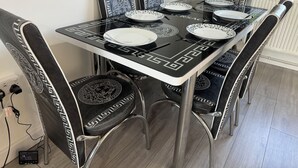 Une table à manger entourée de chaises aux motifs géométriques en noir et blanc, une nappe noire ornée d’un motif géométrique et des assiettes blanches.