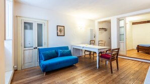 A room with a blue sofa, a wooden dining table, and a mirror. - Apartment 'Appartamento Nel Cuore Di Volterra' (Volterra)