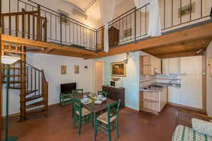 Un espace repas comprenant une table en bois, des chaises et un escalier.