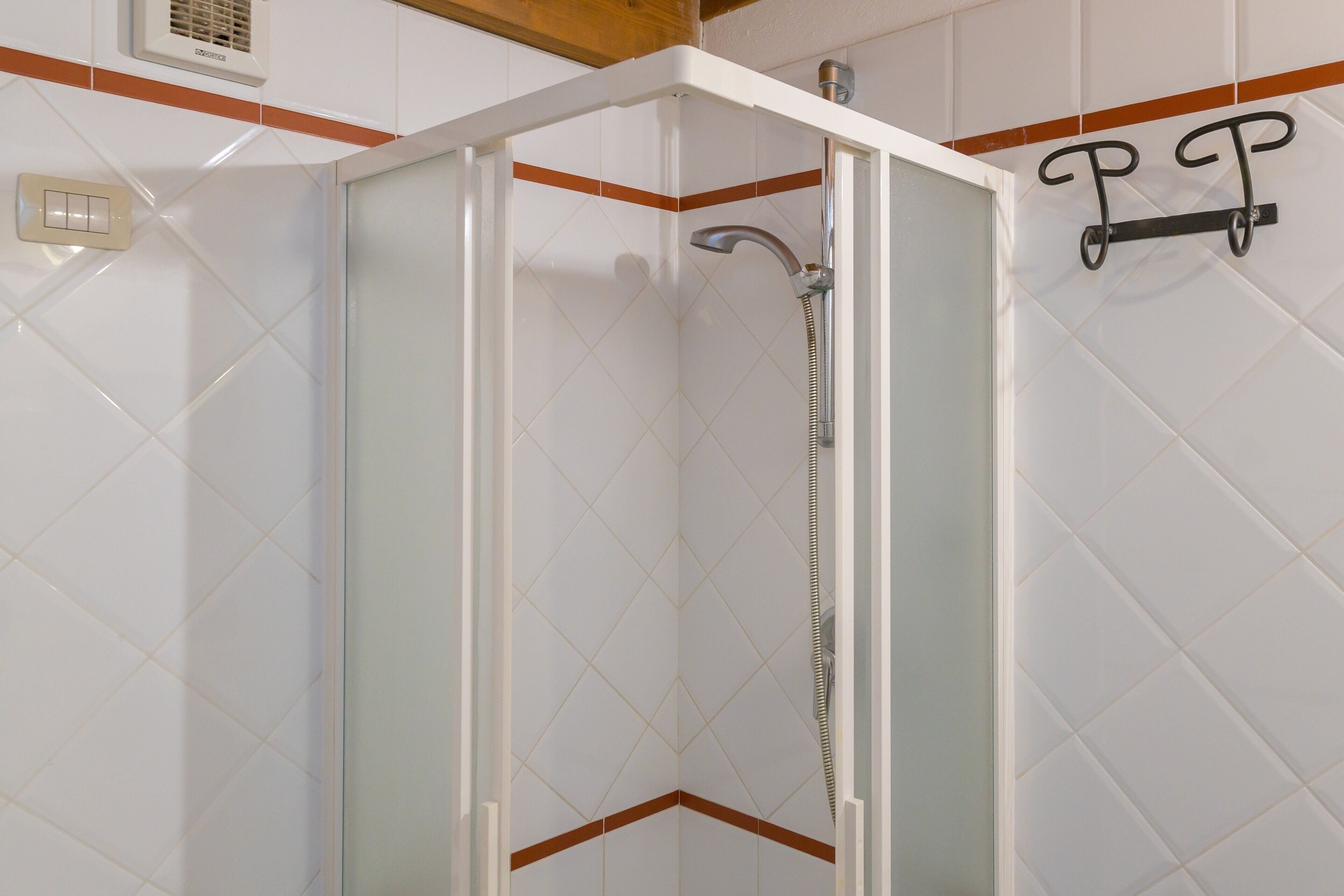 A shower enclosure with a glass door, a showerhead, and a towel rack.