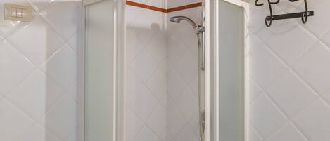 A shower enclosure with a glass door, a showerhead, and a towel rack.