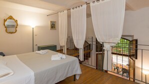 Ein Schlafzimmer mit Bett, Nachttisch, Spiegel und einem Fenster mit Vorhängen.