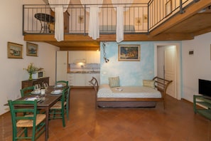 Une chambre avec un lit, une table à manger avec des chaises, un coin cuisine et un balcon.