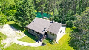 Ein eingeschossiges Haus mit einer überdachten Veranda, umgeben von dichtem Wald.