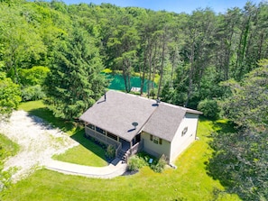 Une maison de plain-pied dotée d’un porche abrité, entourée d’une forêt dense.