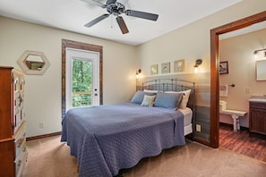 Una camera da letto con un letto, una ventola a soffitto, una porta che dà su un balcone e un bagno piccolo.