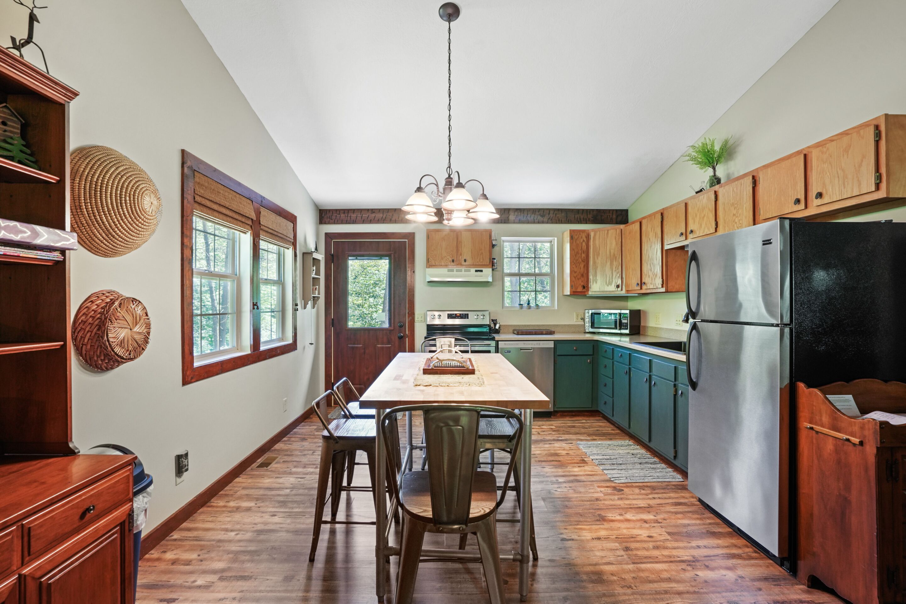 A kitchen with wooden cabinets, a stainless steel refrigerator, and a dining area with a table and chairs.