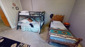 A room with a bunk bed and a single bed, both with patterned bedding. - Boondocks Bungalow | Hocking Hills, 18 Acres, Pond (New Plymouth)