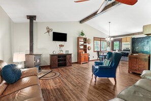 Una sala de estar acogedora con chimenea, sofás de cuero, televisor y una cocina al fondo.