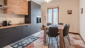 A modern kitchen with grey cabinets, a wooden countertop, and a dining area with a table and chairs.