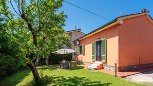 A house with a patio, a table with chairs, and a tree.