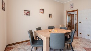 A dining area with a wooden table, six chairs, and three wall-mounted pictures.