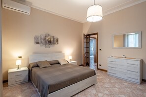 Une chambre à coucher comprenant un lit, des tables de chevet, une commode, un miroir et un luminaire au plafond.