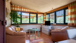 A living room with a sofa, a small table, a television, and a window with curtains. - Villa 'Casa Rocco, Private Pool' with Private Pool, Wi-Fi and Air Conditioning (Ceglie Messapica)
