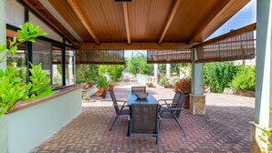 A covered patio with a table and chairs, potted plants, and a view of the garden. - Villa 'Casa Rocco, Private Pool' with Private Pool, Wi-Fi and Air Conditioning (Ceglie Messapica)