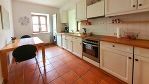 Una cocina con una mesa de comedor, sillas, lavadora, horno y ventana.