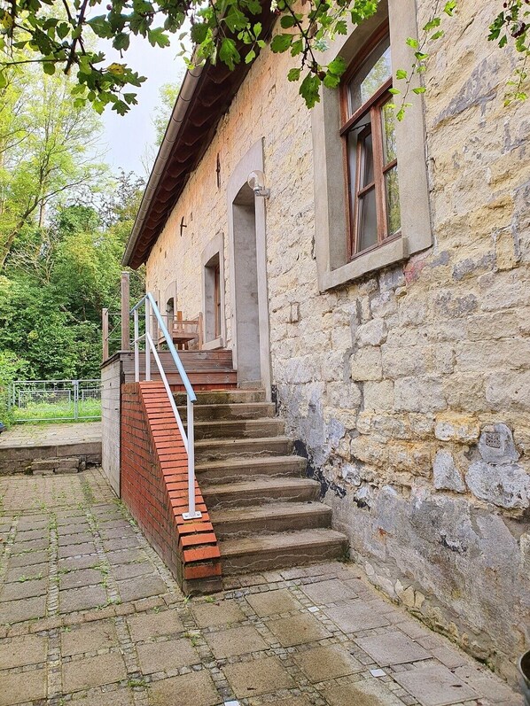 A stone building with a staircase leading to a wooden door.