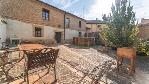 A courtyard with a brick building, outdoor furniture, and a wooden table.