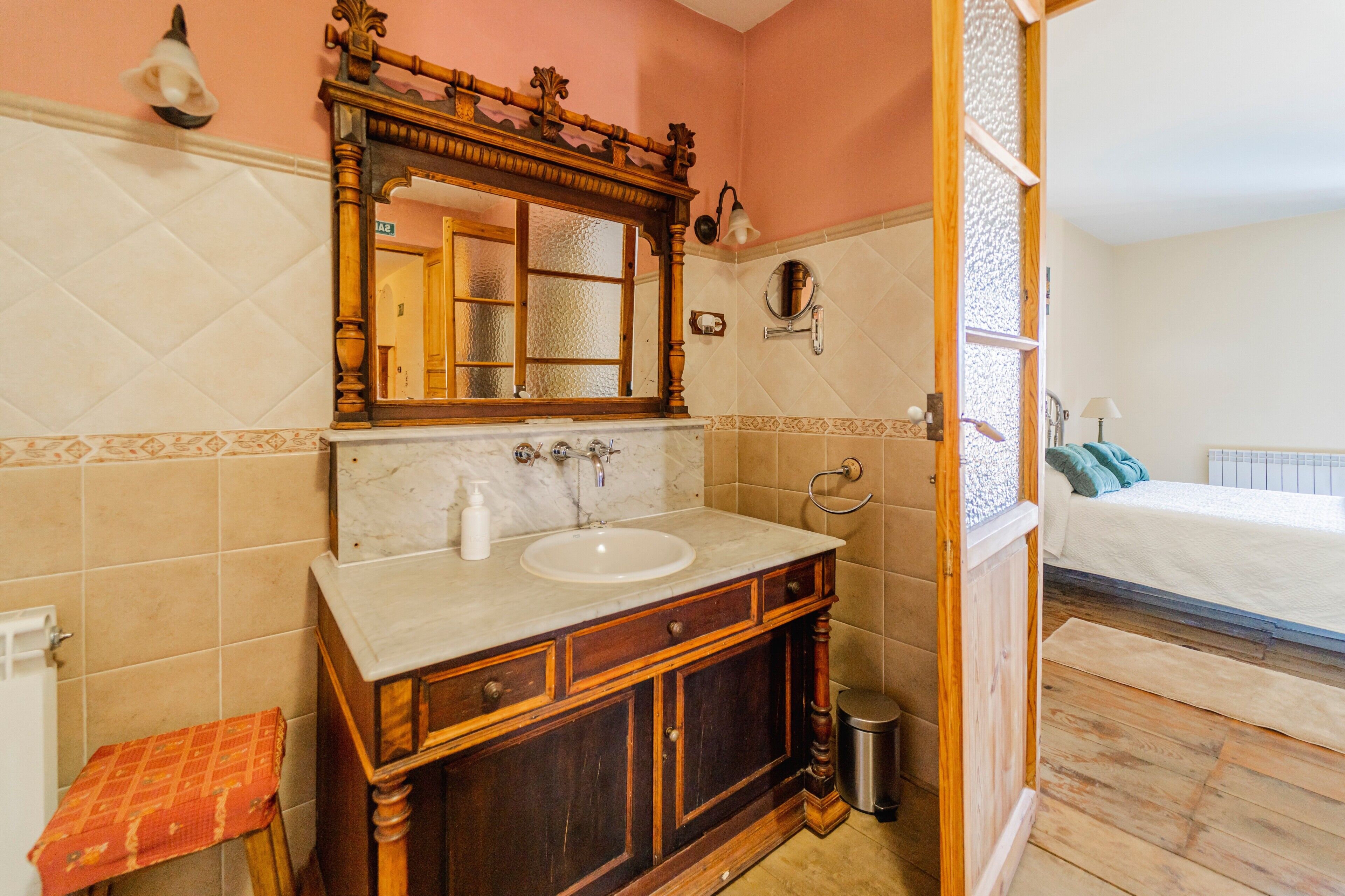 A bathroom with a wooden vanity, a large mirror, a sink, and a toilet.
