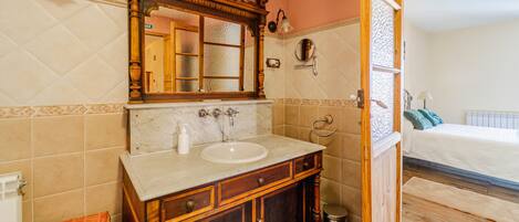 A bathroom with a wooden vanity, a large mirror, a sink, and a toilet.