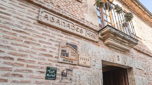 A rustic building facade with a sign reading 'ABANADES' and a number '5' above a doorway.
