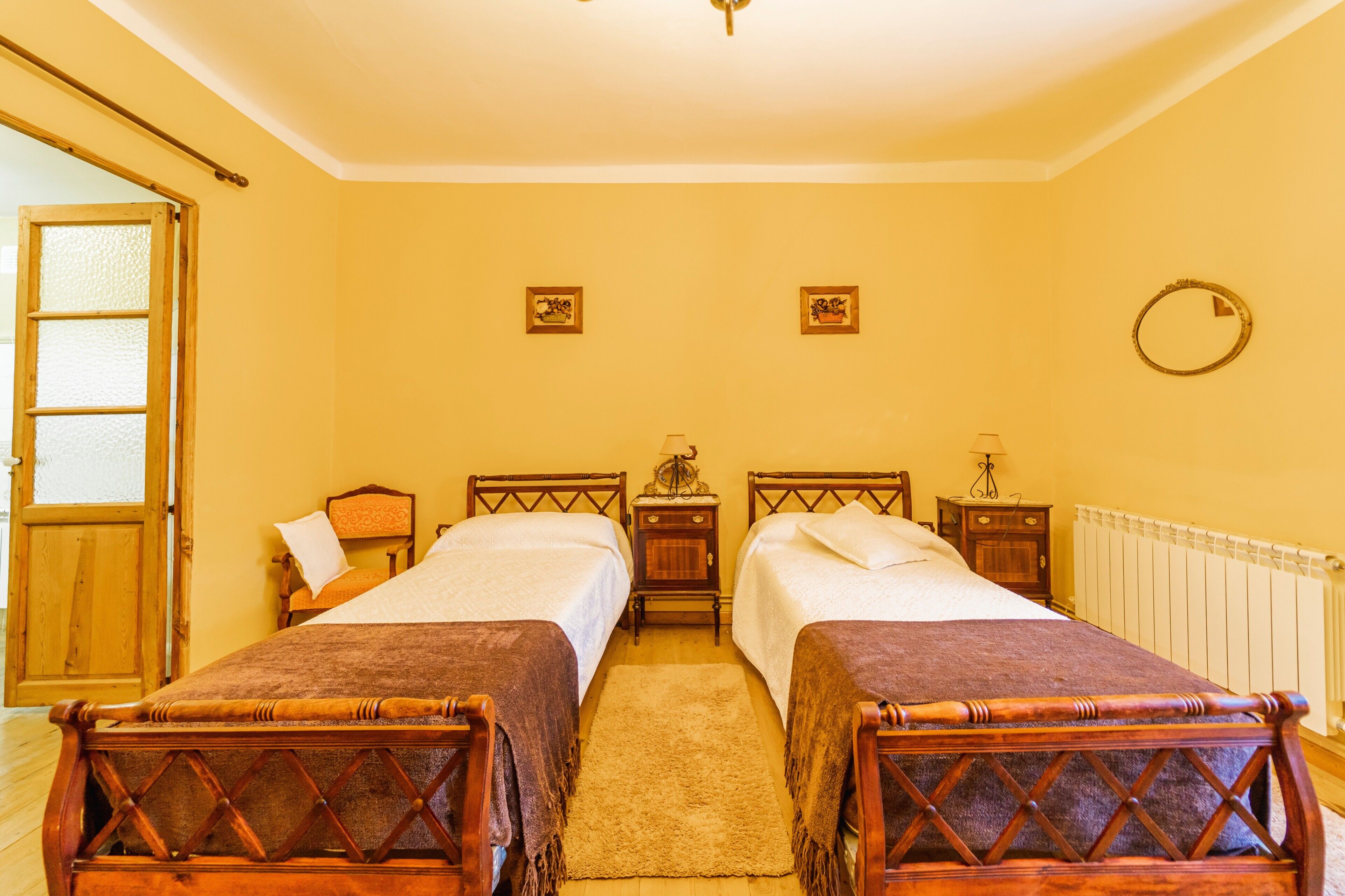 Habitación con cama doble, dos mesitas de noche, una puerta de madera y un radiador.