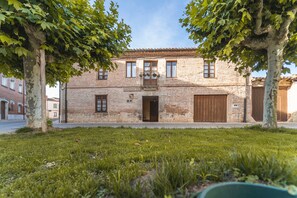 Un edificio in mattoni di due piani con un ingresso centrale, un piccolo balcone e una porta in legno.