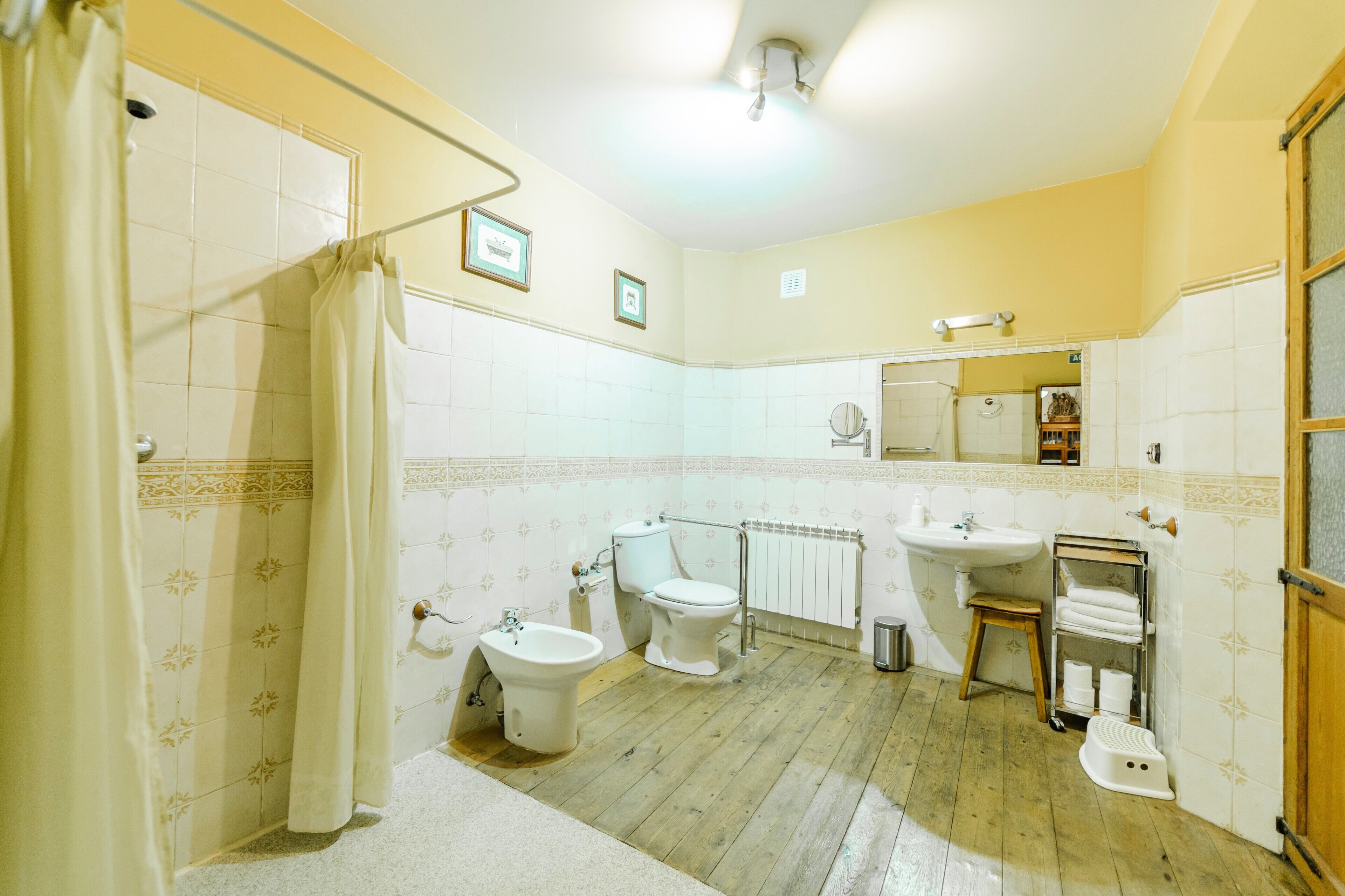 Ein Badezimmer mit Dusche, Bidet, Toilette, Waschbecken und einem kleinen Hocker.