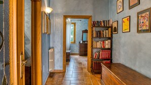 Un couloir avec une porte en bois, une bibliothèque et des tableaux encadrés accrochés aux murs.