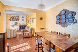 A dining area with a wooden table and chairs, a sofa, and a television.