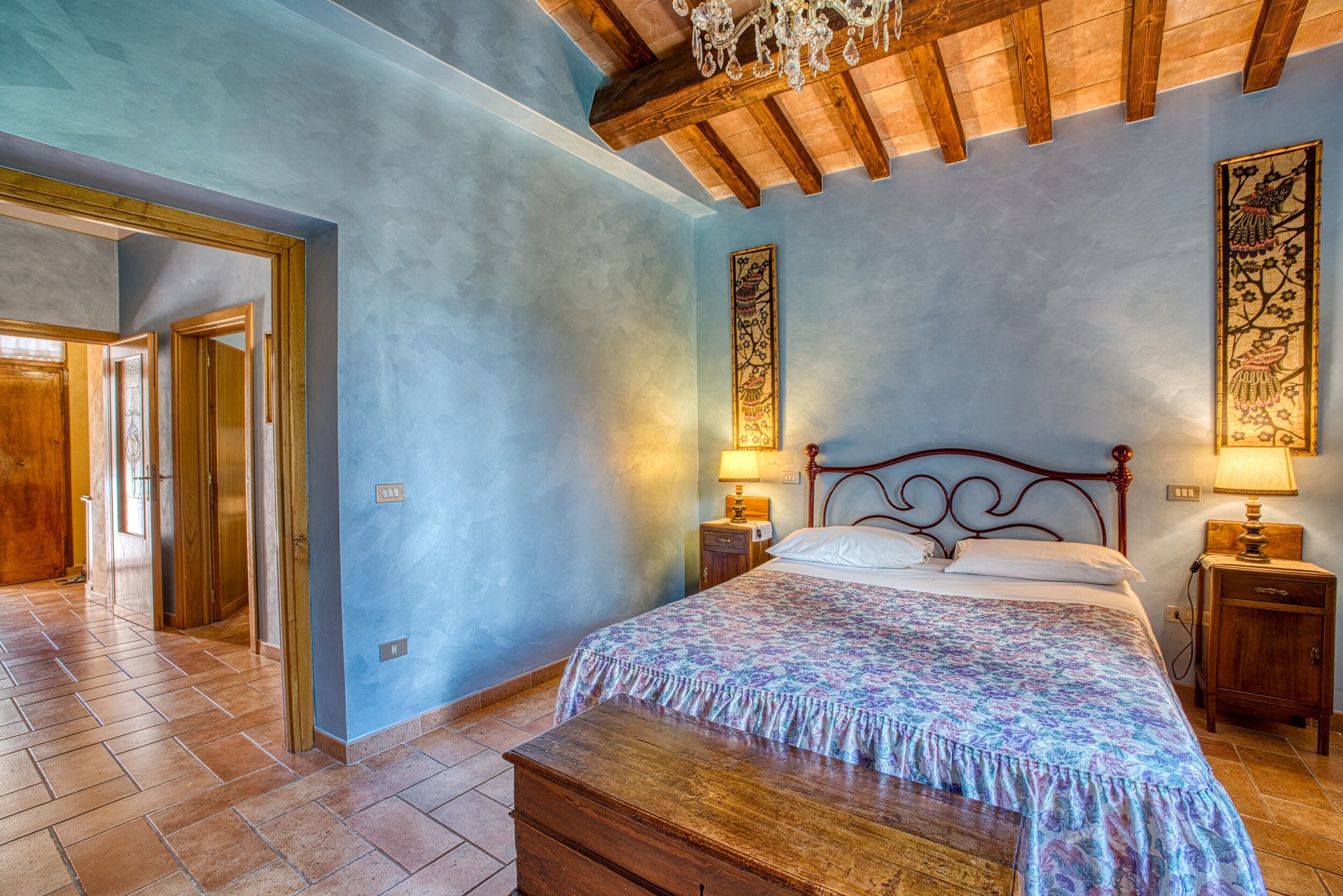 Una camera da letto con un letto di legno, un comodino, una panca e un lampadario.